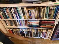 Bookshelves filled with rows of paperback and hardcover fiction titles on two shelves