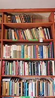 Shelf with various vintage and antique books including hardcover editions in different sizes and colors.