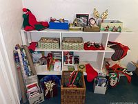 White shelf with assortment of Christmas decorations, wrapping supplies, greeting cards and stockings