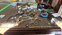 Overhead view of assorted costume jewelry pieces spread on tabletop including bracelets, necklaces, brooches