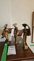 Set of three Mid Century Modern gilded iron Odori dancer figurines displayed on a wooden surface.