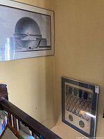 Two framed art prints displayed on a stairwell wall, one geometric and the other spherical design.