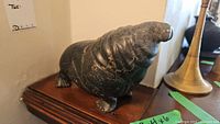 Side view of black basalt walrus sculpture on wooden surface