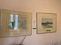 Two silver-framed prints hung side by side on pink wall