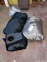 Two packed air mattresses and an insulated lunch bag resting on a floor