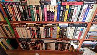 Three shelves of assorted VHS movie tapes displayed front-facing