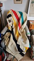 Vintage Eaton Trapper Point all wool blanket draped over a chair showing multicolor stripes on a cream base.