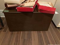 Front view of the vintage wooden chest trunk with red boxes on top.