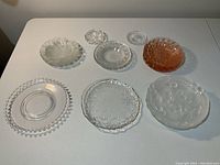 Full assortment of 22 glass dishes and coasters shown on table, including various sizes and decorative patterns.