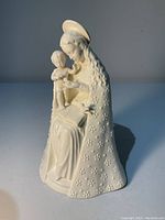 Front and partial side view of the Flower Madonna figurine showing the detailed floral-patterned cloak and seated child on lap.