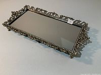 Side angled photo showing the metal frame's intricate rhinestone pattern and mirrored surface of the vanity tray.