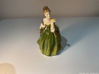 Front view of the Royal Doulton porcelain figurine Fleur with detailed dress and flower in hand.