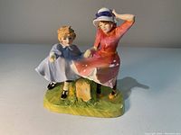 Front view of the Royal Doulton figurine showing woman in red dress holding boy's hand beside milestone stone.