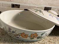 Ovenware dish with lid open showing inside of dish and side floral design.