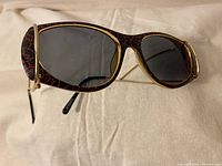 Front view of Paloma Picasso sunglasses showing the black and red crackle pattern with gold-tone edges.