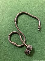 Pandora sterling silver bracelet coiled on green surface showing clasp and chain detail