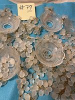 Overhead image showing the vintage chandelier parts including frosted grape-shaped crystal clusters and 4 textured clear glass cups on a blue cloth background.