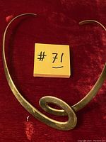 Vintage copper V-shaped necklace with an abstract loop feature on a red velvet background with a lot number note.