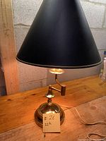Full view of the lamp showing the large black conical shade and brass base with a handwritten note indicating '22h'.