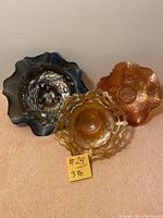 Front and slightly angled view of three vintage carnival glass candy dishes showing iridescent colors and distinct patterns.