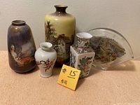 Five assorted miniature vases and a decorative piece shown on a beige surface against a neutral wall