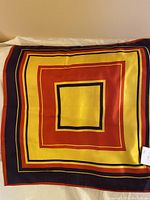 Full view of scarf laid flat showing yellow, orange, and blue geometric square pattern.