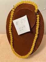 Full length view of necklace displayed on brown velvet jewelry mount with a note showing 22 inch length.