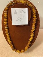 Full view of the Baltic amber necklace laid on a brown velvet jewelry display, showing the arrangement and length of the necklace.