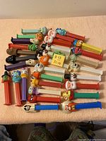 Top view of all 30 Pez dispensers laid out on surface, showing variety of characters and stem colors