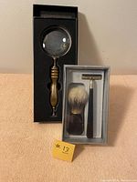 Photo showing the shaving kit with razor and shaving brush in box, and the magnifying glass in box.