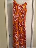 Full front view of the vintage Hawaiian maxi dress on hanger showing sleeveless design and vibrant floral pattern.