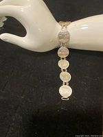 Full view of the silver coin chain link bracelet displayed on a mannequin's wrist showing coin details and overall length.