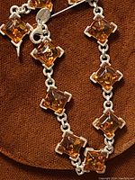 Close-up of the bracelet showing square amber stones in sterling silver settings, lobster clasp and part of the chain link.