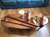 Photo showing entire lot of African wood art items on wooden table including masks, canes, drum, and figurines