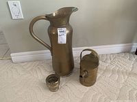 Photo showing all three brass items: tall jug, small watering can, and small jar with perforated lid