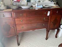 Front view of dark wood buffet sideboard with four drawers and two cabinet doors with wood inlay.