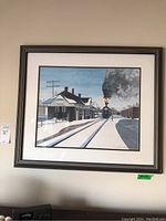 Full view of framed signed limited edition train station print hung on wall.