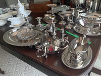 Full view of the 11-piece silver plated serving ware set arranged on a table, including candle holders, salt and pepper shakers, gravy boat, platter, and plates.