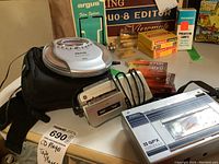 Overview of all audio devices including Sanyo portable CD player, GE miniature tape recorder, GPX cassette player, blank tapes, carrying case, and cables.