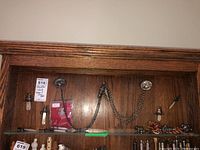 Wooden cabinet shelf with assorted vintage whistles, chains, badge and rattles