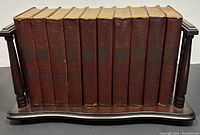 Ten red cloth bound volumes of The Modern Readers Shakespeare displayed on mahogany barrister bookcase