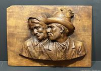 Front view of the realistic hand carved wooden portrait of an elderly couple with detailed facial features and clothing.