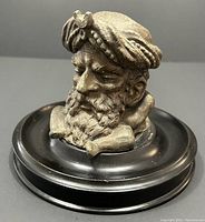 Close-up front angle of metal bearded Turk inkwell on black wood base showing detailed facial features and turban.
