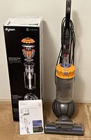 Dyson DC66 vacuum upright with original box and user manual placed on floor.