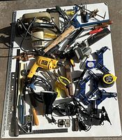 Wide view capturing an assortment of hand and power tools including a yellow drill, jigsaw, clamps, hammers, screwdrivers, and measuring tools.
