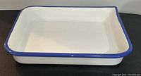 Photo showing the full side profile of the white enamel photographic tray with blue rim, highlighting depth and shape.