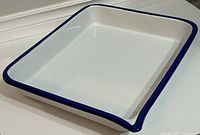 Angled view showing white enamel tray with a smooth blue rim and no visible defects.