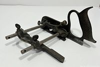 Side angled shot of the vintage Record No 050 combination plane showing the metal rods and cast iron handle with textured surface.