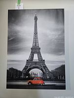 Front view of a black and white wrapped canvas print featuring the Eiffel Tower with a red vintage car in the foreground.