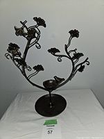 Burnished bronze jewelry stand shown from front on a white surface with numbering label.